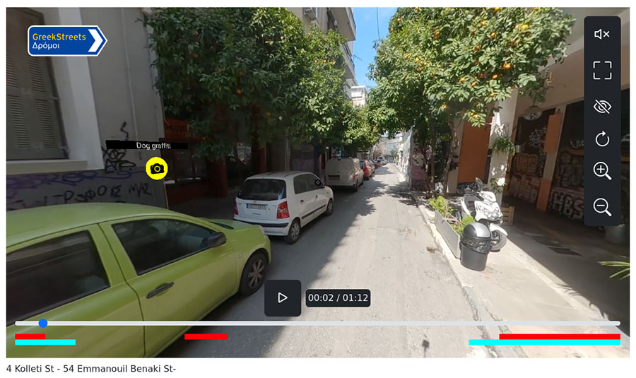 A screen-capture of 360-degree video of the street around 4 Kolleti St and 54 Emmanouil Benaki St in Greece. The street is lined with parked cars on the left, and on the right is a building whose wall is covered in graffiti. A yellow circle with camera icon on the wall indicates the link to a detailed photo view.